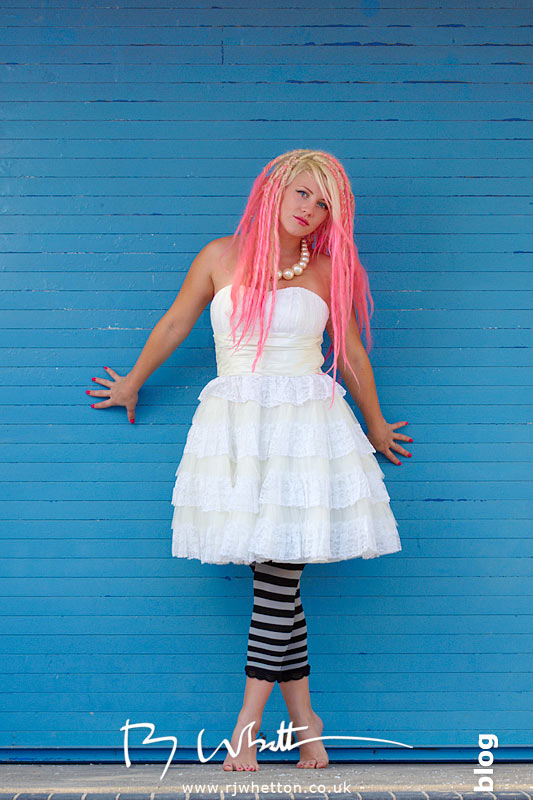 Pixie posing in an Eastenders wedding dress against a blue beach hut door 