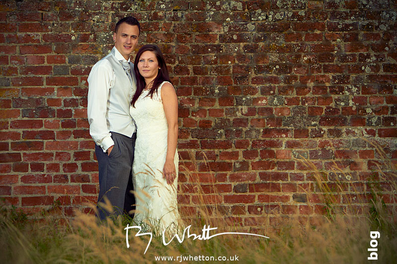 Stacy and Darren posing in front of an old wall in Christchurch, Dorset - Wedding Photography Dorset